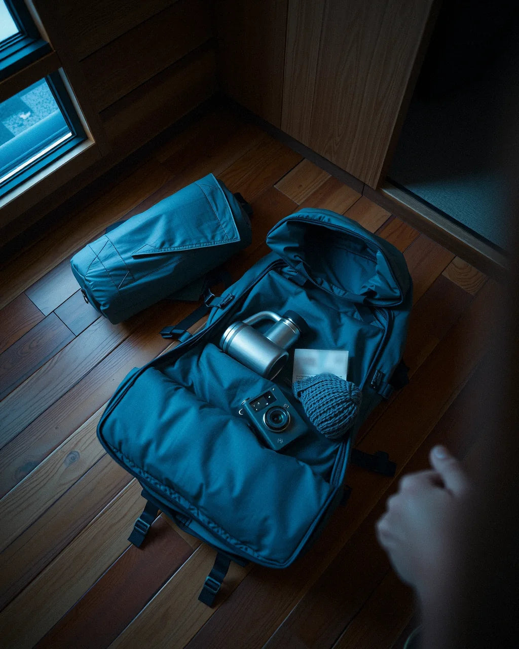 A backpack being packed on a cabin floor at dawn