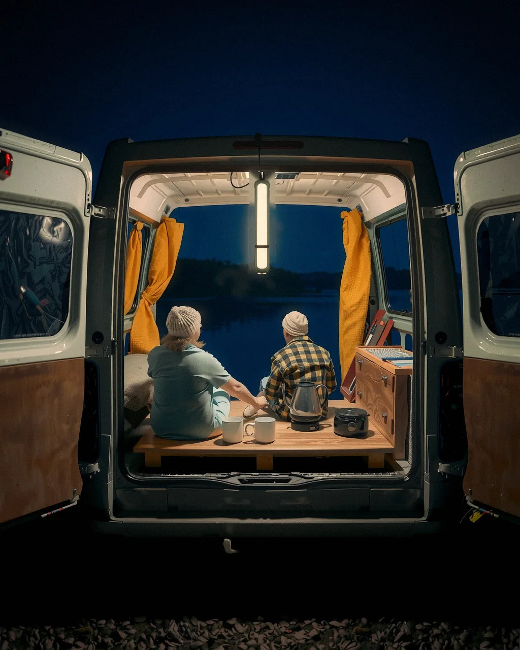 An Adventure Lamp lighting a camper van by a lake at night